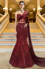 Deep maroon mermaid lehenga with heavy sequin embroidery, corset blouse, and sheer embroidered cape.