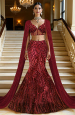 Deep wine red mermaid lehenga with heavy sequin embroidery and sheer net cape with linear designs.