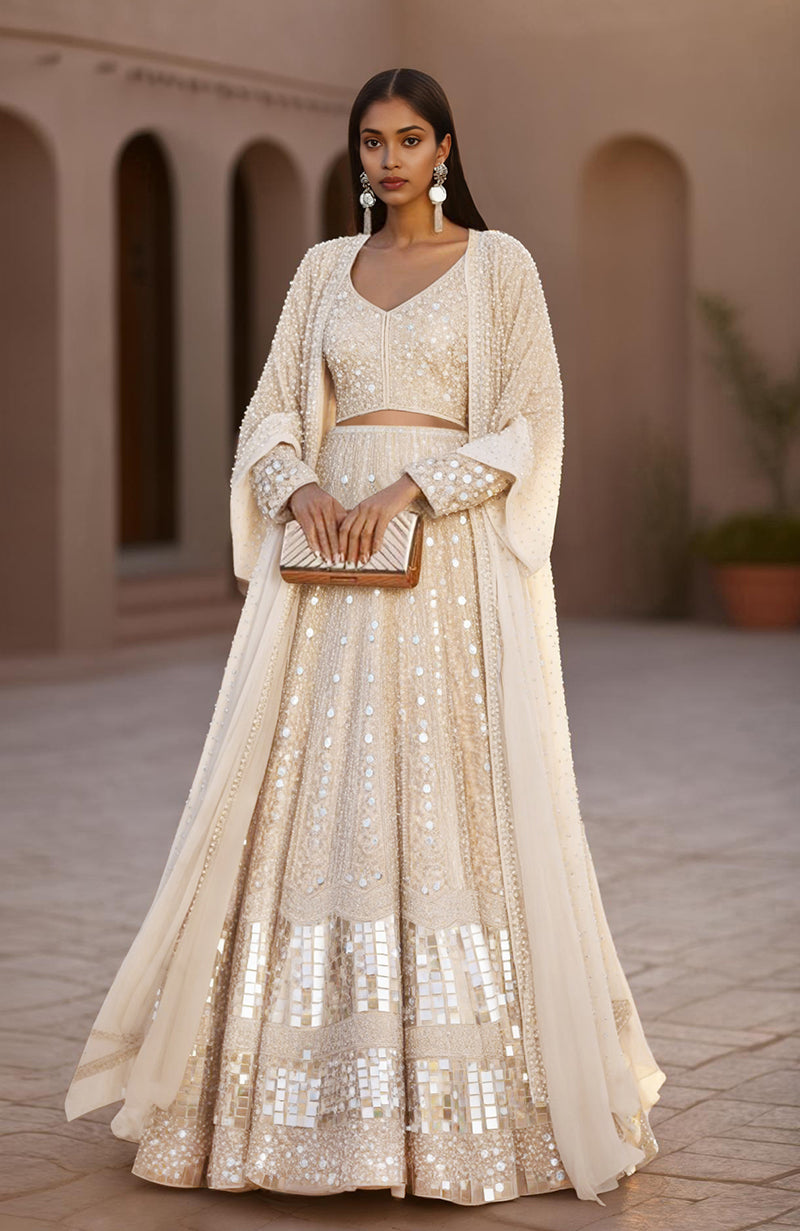 Champagne-colored lehenga set with hand-embroidered mirrors, sequins, pearls, and sheer cape.